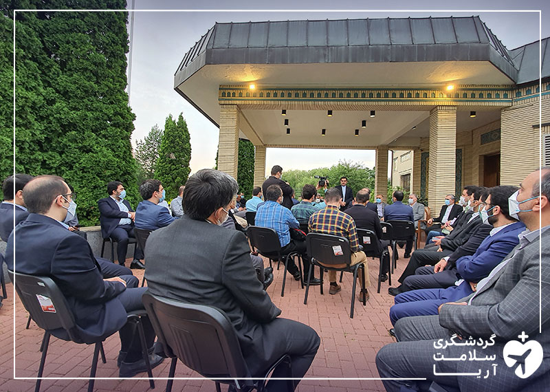 تعدادی آقا در حیاط ساختمان سفارت ایران در روسیه روی صندلی نشسته اند و جلسه در حال برگزاری است.