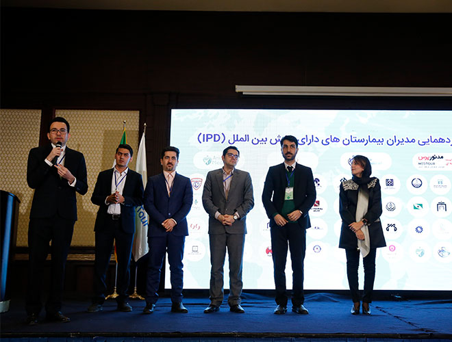 AriaMedTour's president Hadi Shajari giving a lecture during the health tourism conference held in Tehran, with other AriaMedTour'sstaff seen in background