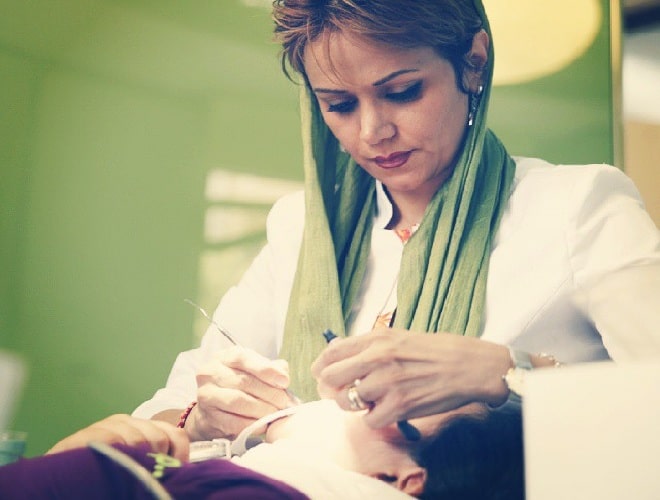 female iranian dentist performing dental veneers for patient