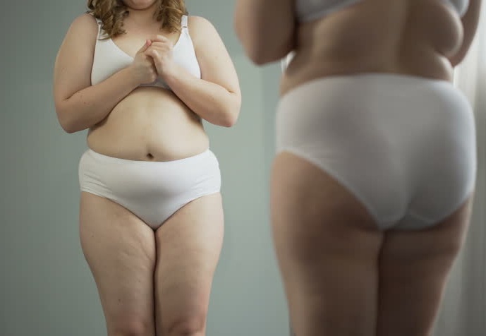 fat woman with fat thighs and abdomens standing in the front of a mirror