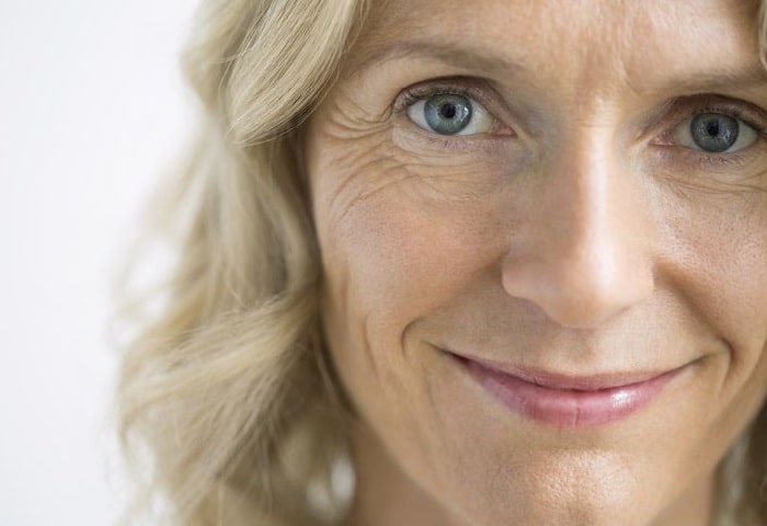 woman with wrinkles around eyes smiling in front of the camera 