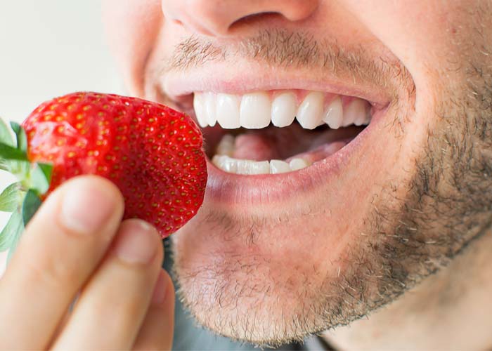 dental implants patients about to bite at a strawberry