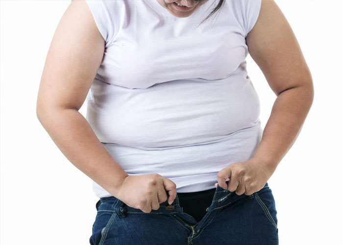 obese woman trying to button jeans