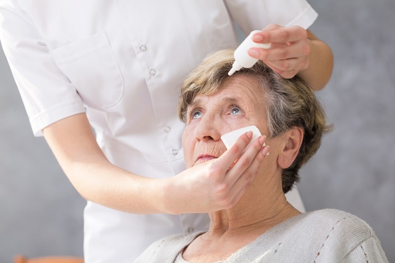 doctor in white applying eye drops