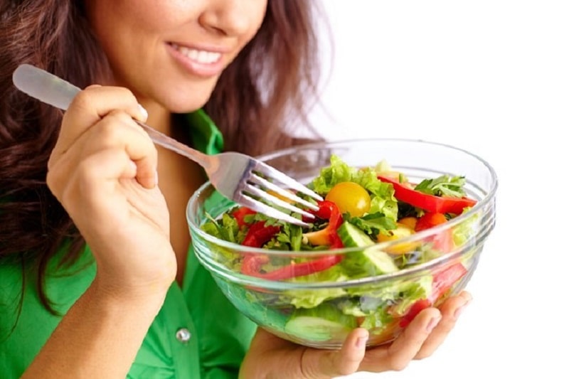 woman eating green salad out of a bowl 