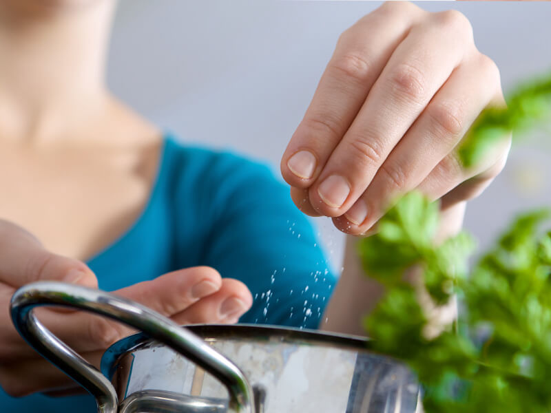 woman adding a pinch of salt to her food