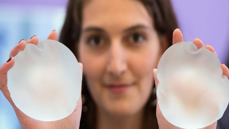 woman holding breast implants in her hands