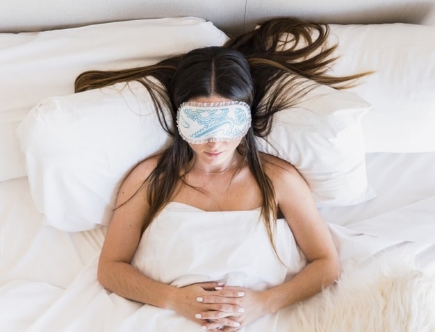 woman sleeping after breast augmentation in bed with elevated head and shoulders