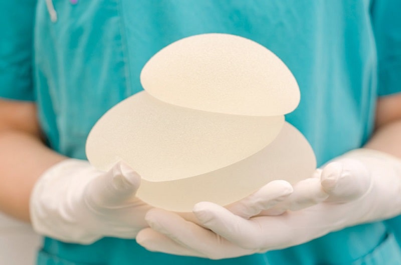 surgeon holds three breast implants with different sizes