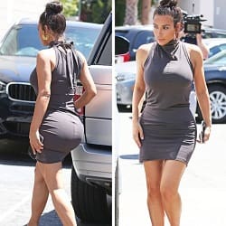 Kim Kardashian in a grey tight dress walking next to a car with her round derriere and ample breasts standing out
