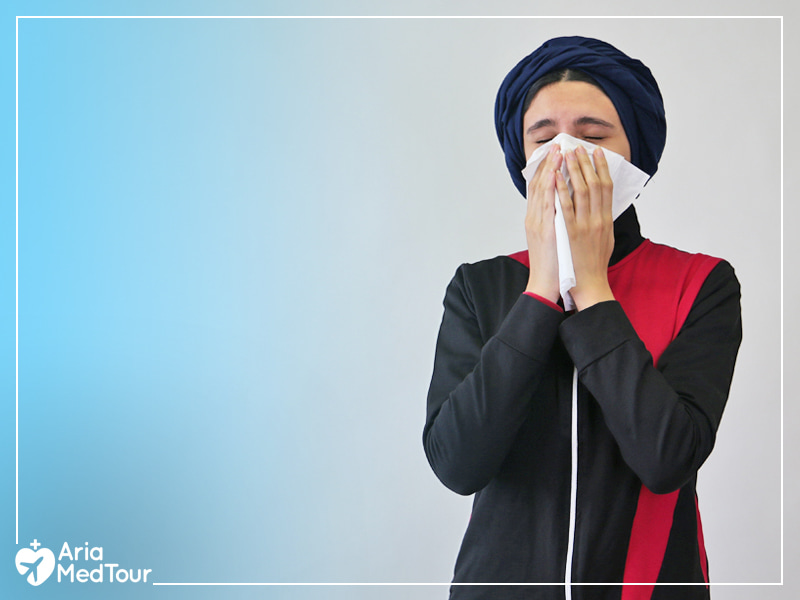 Muslim girl covering her nose and lips with a tissue as she is sneezing due to allergy