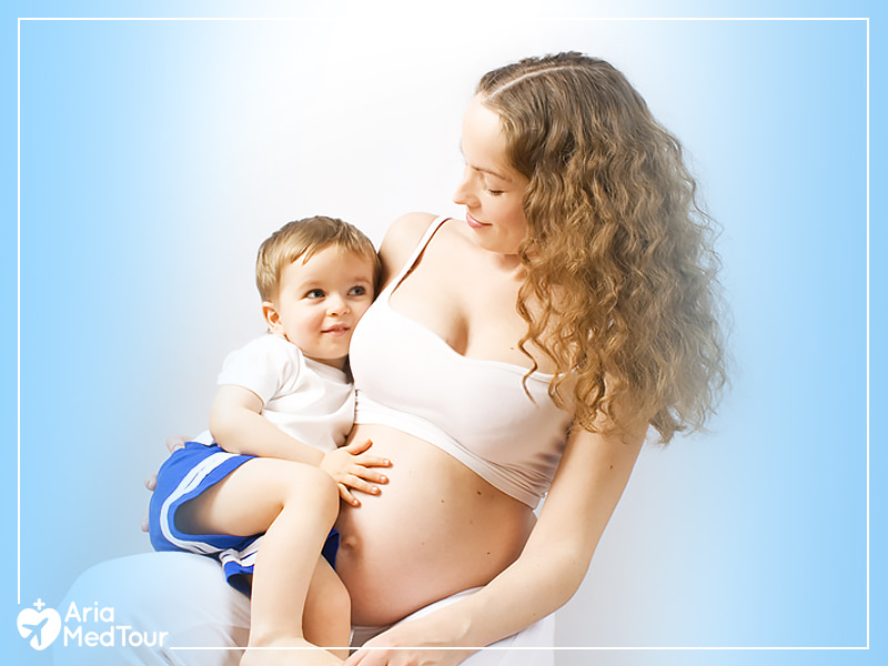 woman hugging her baby and looking at her after getting her breast surgery done