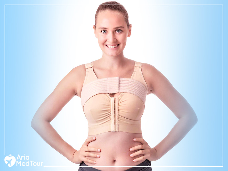 smiling woman wearing a post-operative bra to support her breast implants during the recovery