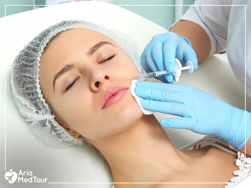 doctor wearing blue gloves injecting dermal fillers into the laugh line of a woman