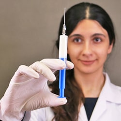 female anesthetist holding a syringe filled with intravenous sedative drug