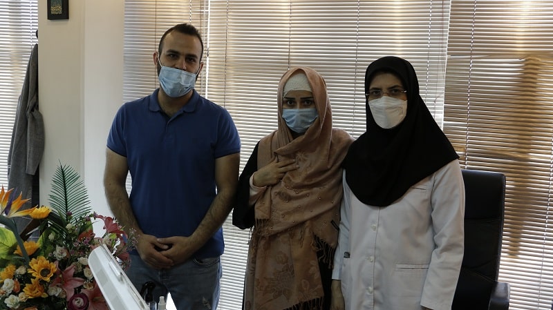 Dr. Masoumeh Saeedi standing next to her patients in her office