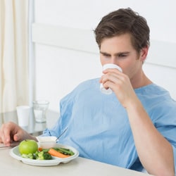 A young man in a blue suit eating and drinking before surgery